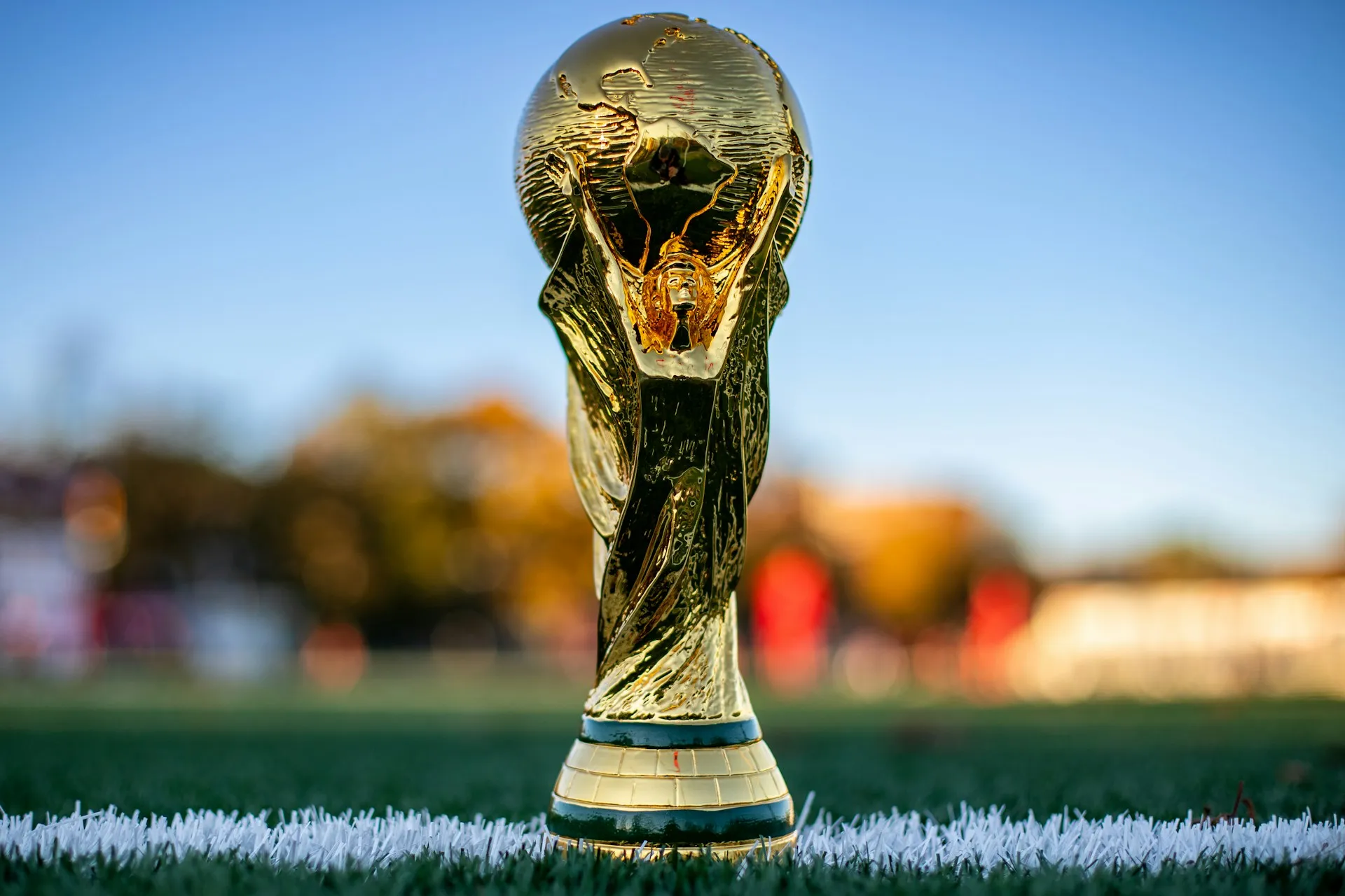World Cup trophy on a football pitch under stadium lights